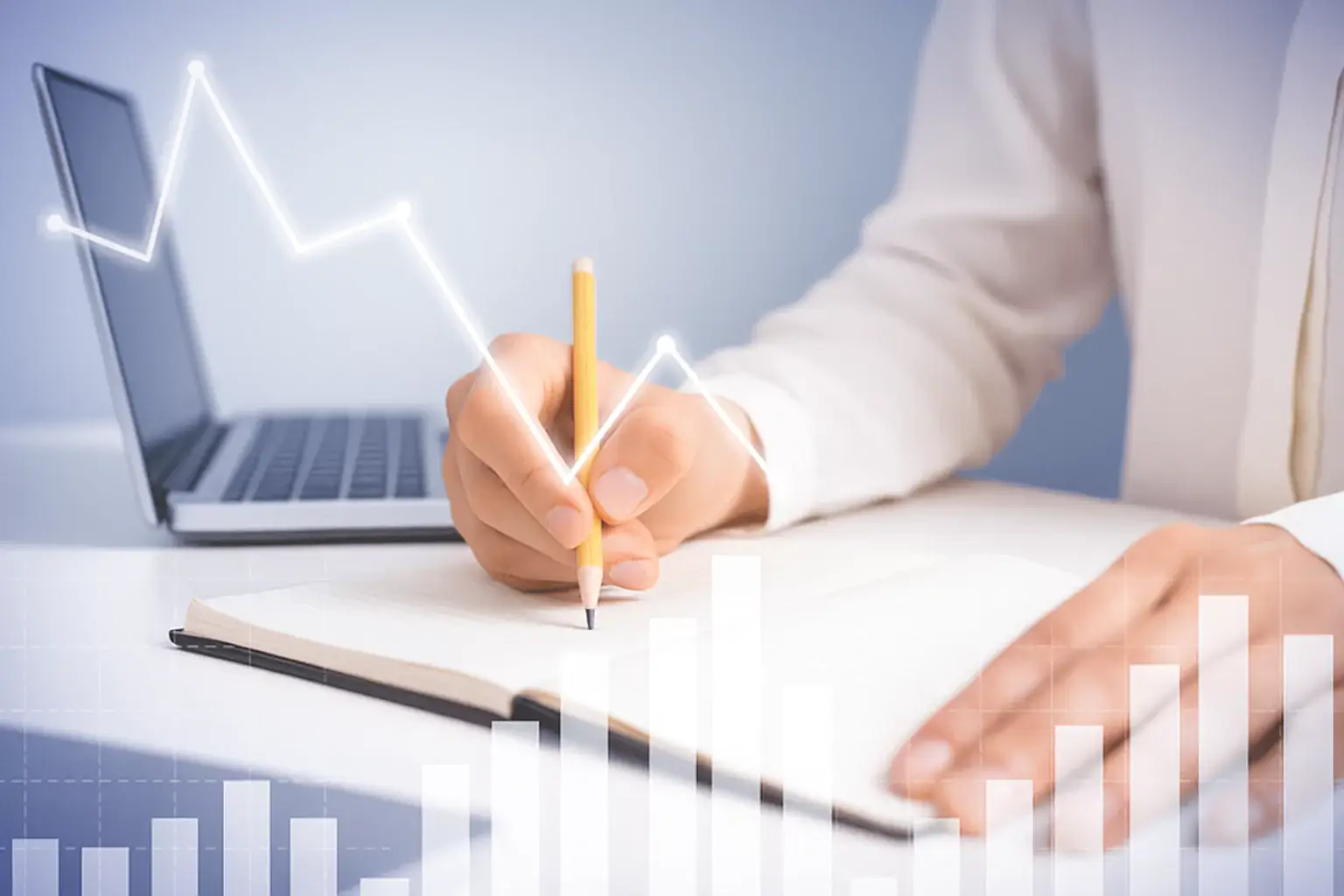Person in a white shirt writing in a notebook next to a laptop, with overlaid bar and line graphs representing educational progress and analytics